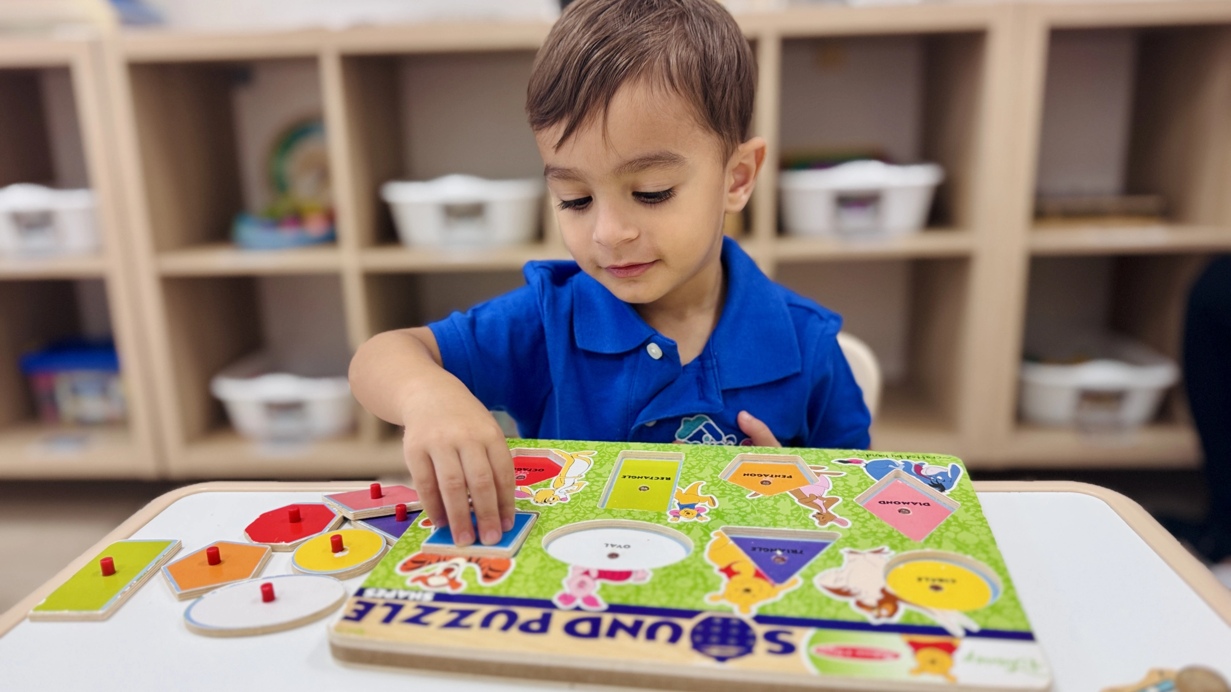Toddler playing with wooden alphabet puzzle at MiniArt Childcare
