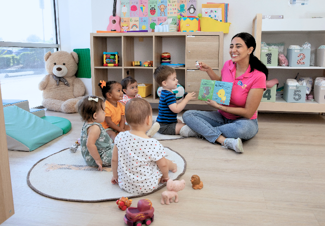 Teacher reading book to toddlers and infants at MiniArt