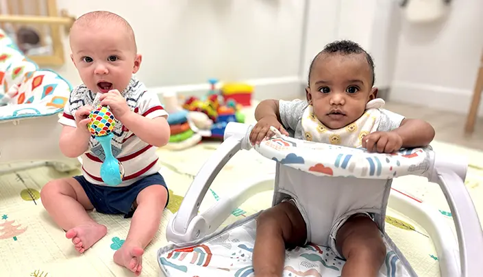 Two cute babies playing on playmat